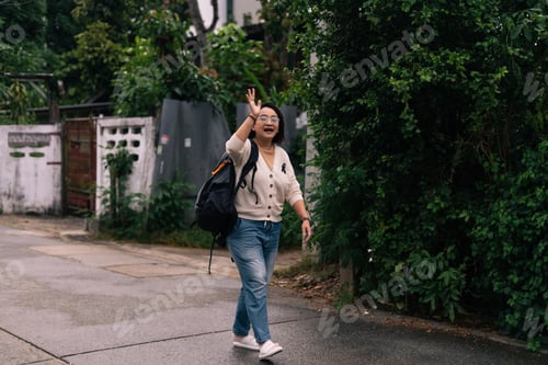Preview: Asian woman traveler waving hand, walking on urban street enjoying journey