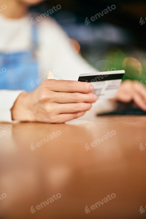 Preview: Close-up of a female hand holding a credit card, reading informations.