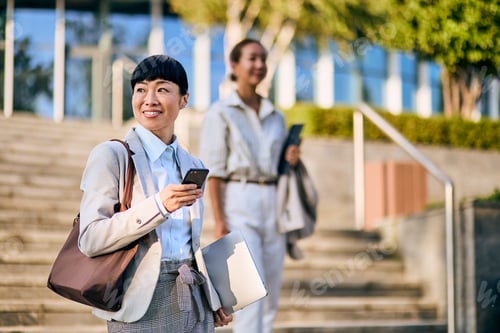 Preview: Asian Business Woman Outdoors Holding Smartphone and Laptop in Office Setting