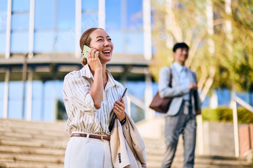 Preview: Asian Business Woman Talking on a Phone Outdoors Near an Office Building