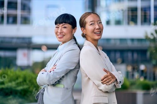 Aperçu: Confident Asian Businesswomen Standing Back-to-Back in Corporate Outdoor Setting