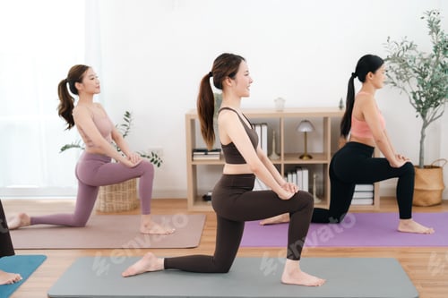 Preview: Kneeling stretch in calm yoga class with three women in bright studio