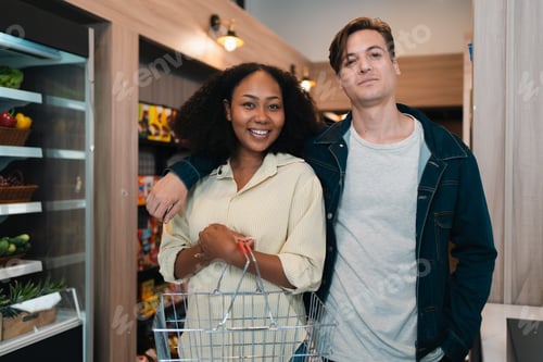 Preview: Smiling couple shopping in grocery store with shopping cart