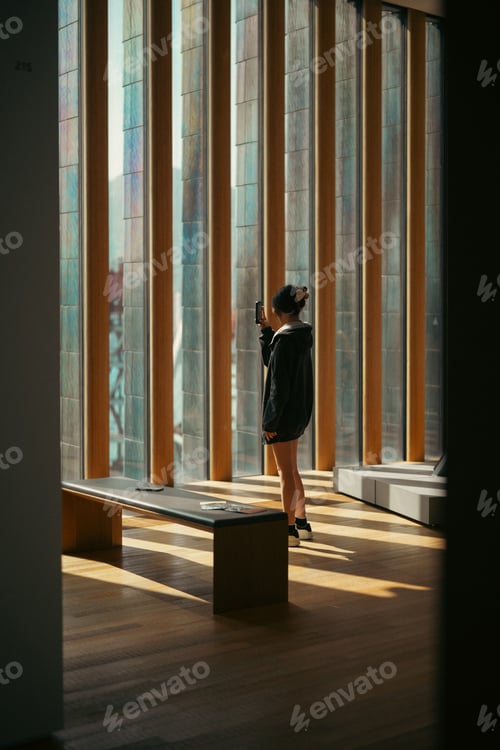 Preview: Woman standing by window in modern interior