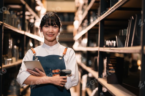Preview: Warehouse worker holding tablet and scanner, smiling in storage aisle
