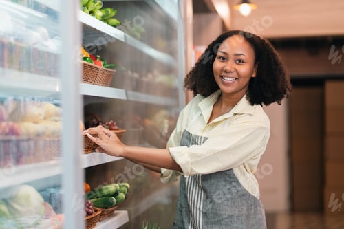 Preview: Smiling woman arranging fruit in market aisle