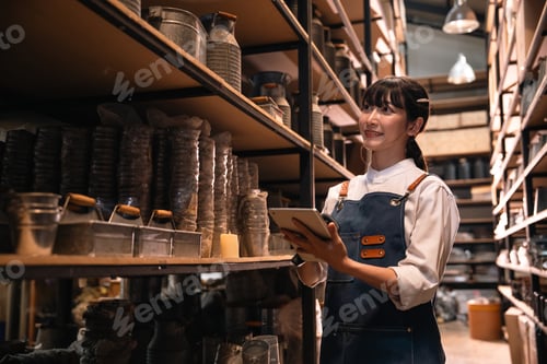 Preview: Retail worker with tablet in storage aisle, smiling in warehouse inventory room