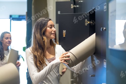 Preview: Young woman placing yoga mat in fitness locker