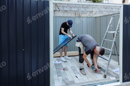 Preview: Two Caucasian workers are assembling a metal shed.