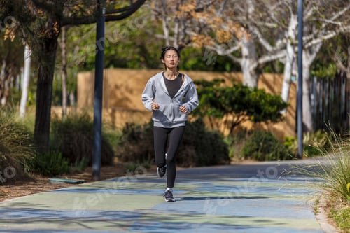 Preview: Young Asian woman jogging in the park on a sunny day