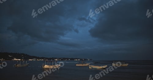 Preview: Boats resting on the shore under a dramatic twilight sky