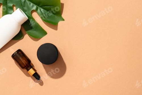 Preview: Natural cosmetic background. Cream jar, serum bottle and tonic on colored background with palm leave