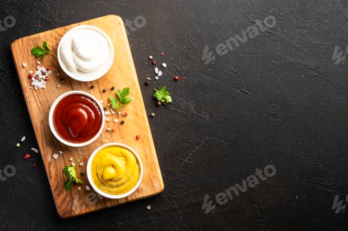 Preview: Ketchup, mayonnaise and mustard in the bowls on black background.