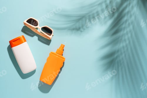 Preview: Sunscreen, sunglasses and seashell on blue background with hard sunny shadows.