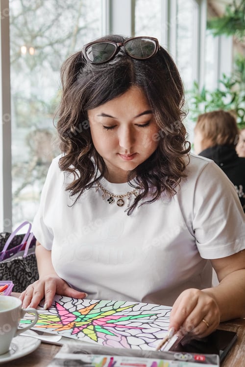 Preview: TVER, RUSSIA - FEBRUARY 25, 2023: Asian woman draws neurographics at table in psychology session, ne