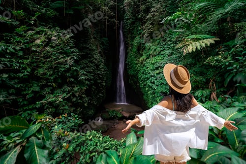 Preview: Solo female traveler with outstretched arms, enjoying freedom and peace in a lush tropical rainfores