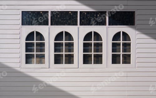 Preview: White wooden house wall with row of glass arch windows and transom lights