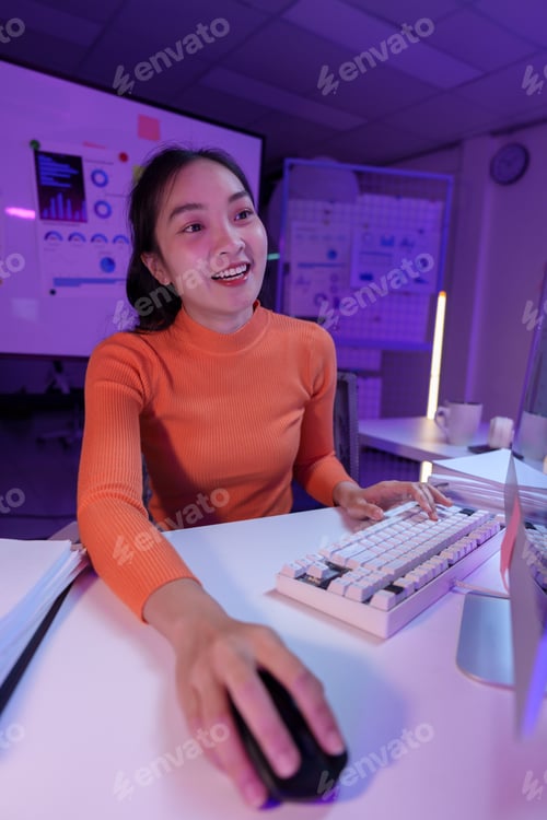 Preview: Enthusiastic young woman in a modern office setting, engaging with a computer. Bright and dynamic en