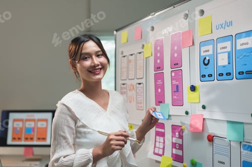 Preview: Attractive female designer points to whiteboard with project of website phone ux ui and explains des