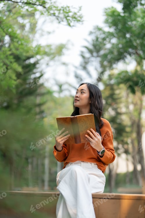Preview: Young woman enjoying outdoor reading, looking away