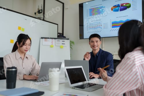 Preview: Business team collaborating while analyzing sales data in meeting room
