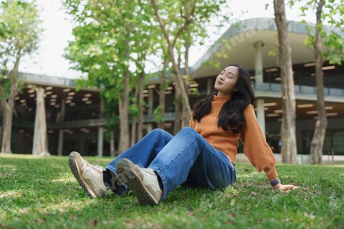Preview: Young woman relaxing on green grass enjoying sun