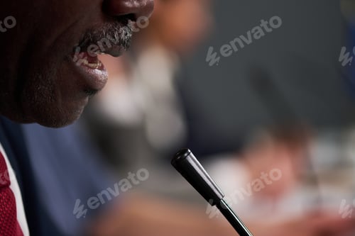 Preview: Black Middle Aged Man Speaking into Microphone at Business Meeting