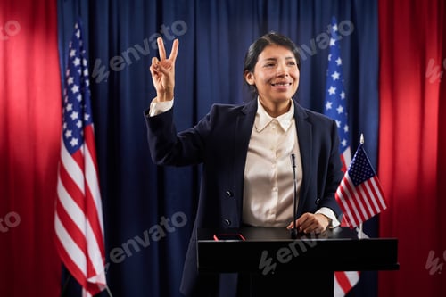 Preview: Hispanic Woman Politician Gesturing Victory Sign at Campaign Podium