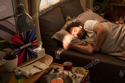 Preview: Adult Man Sleeping Beside Record Player in Home Bedroom