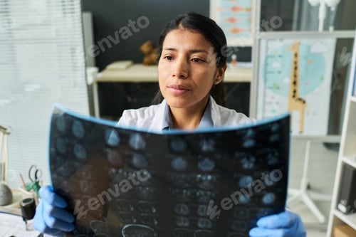 Preview: Hispanic Female Doctor Examining Brain Scan in Clinic