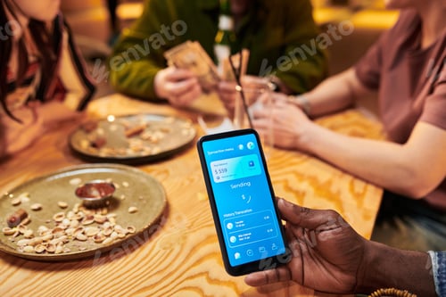 Preview: Black Man Showing Mobile Payment App While Friends Splitting Bill