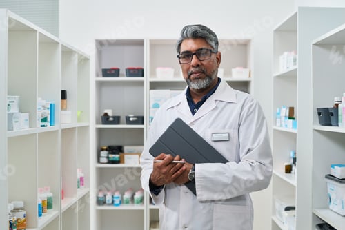 Preview: Portrait of Middle Aged Asian Pharmacist Holding Tablet in Pharmacy