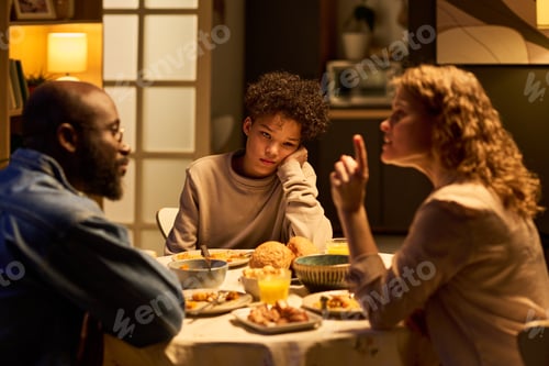 Preview: Teenager Sitting at Dinner Table during Family Conflict at Home