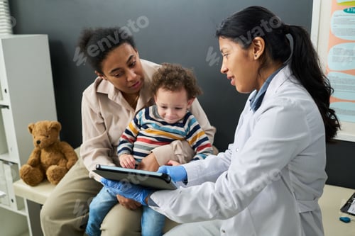 Preview: Female Doctor Advising Black Mother with Toddler in Clinic