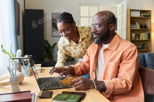 Preview: Black Couple Preparing for Trip While Booking Travel on Laptop