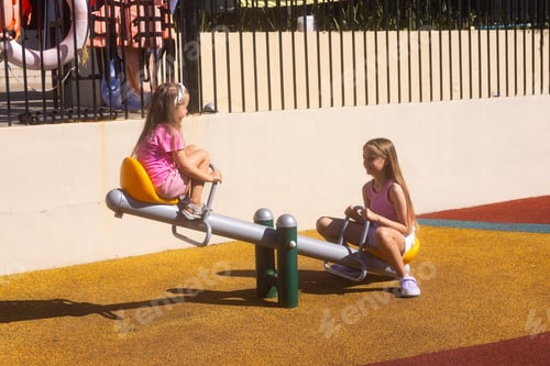 Preview: Two young girls playing on a seesaw at a playground