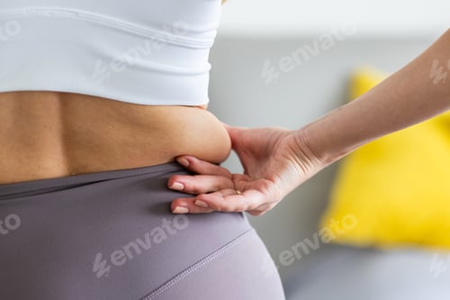 Preview: Close-up of woman pinching skin on waist in activewear