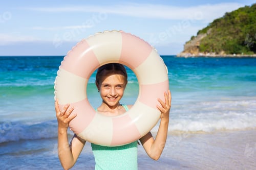 Preview: Smiling girl holding inflatable ring on a beach