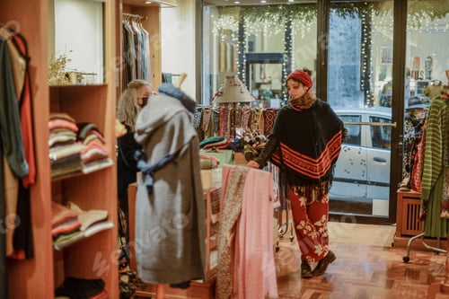 Vista previa: A woman carefully selects fashionable winter clothing from a boutique's diverse collection of season