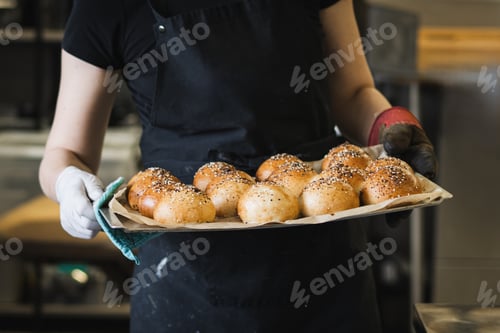 Preview: Smiling Female Baker Holding Fresh Artisan Sourdough Bread in Bakery
