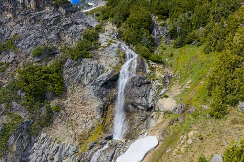 Preview: Alpine Waterfall Cascading Down Rocky Cliff Surrounded By Evergreen Forest In British Columbia, Cana