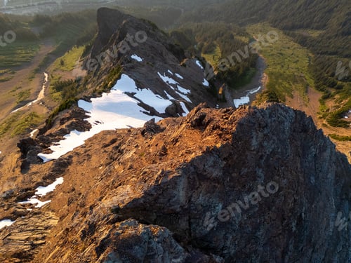 Preview: Aerial View of Rocky Mountain Ridge With Snow Patches and Forested Valley at Sunset in Fraser Valley
