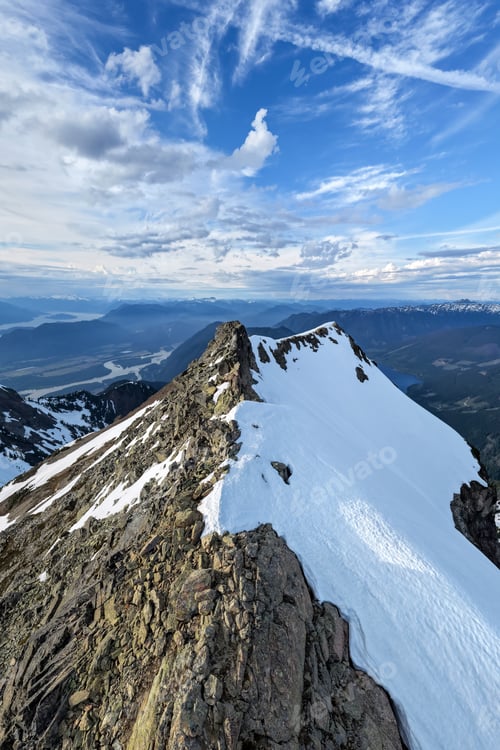 Preview: Snowy Mountain Ridge Summit Overlooking Valley and Lakes Under Dramatic Sky in British Columbia, Can