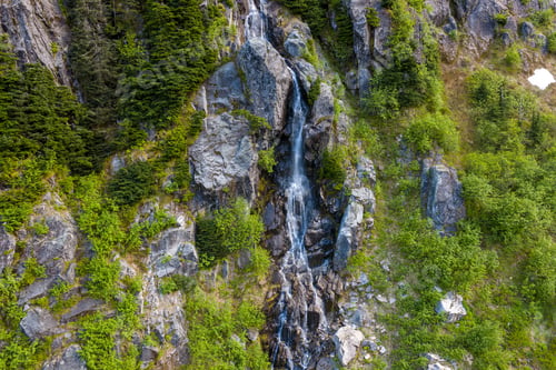 Preview: Narrow Waterfall Cascading Down Rocky Cliff Surrounded by Lush Evergreen Forest in BC, Canada