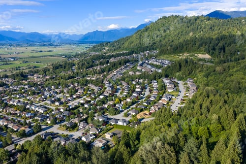 Preview: Aerial View Of Suburban Neighborhood And Forested Promontory Overlooking Farmland In Chilliwack, Bri