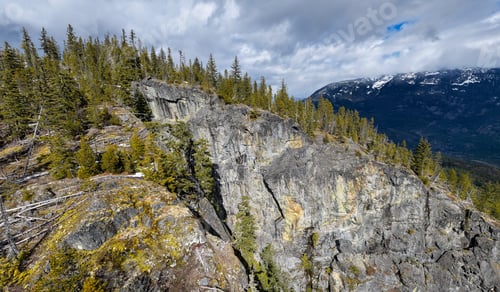 Preview: Rocky Cliff and Evergreen Forest Overlook With Snowy Mountains in the Distance — British Columbia, C