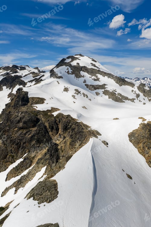Preview: Snow Covered Mountain Peak in British Columbia Canada With Rocky Alpine Ridges and Clear Blue Sky