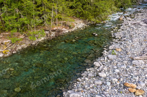 Preview: Clear Rocky Riverbank and Forest Along Harrison Lake BC Canada With Emerald Stream and Driftwood