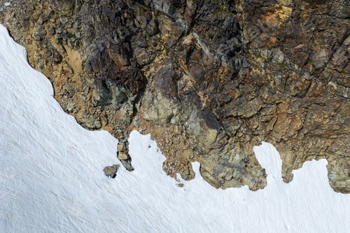 Preview: Aerial View of Rugged Rocky Mountain Edge With Snowfield in British Columbia, Canada