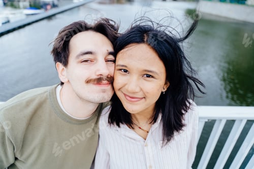 Preview: Close up portrait of happy interracial couple smiling together on city bridge